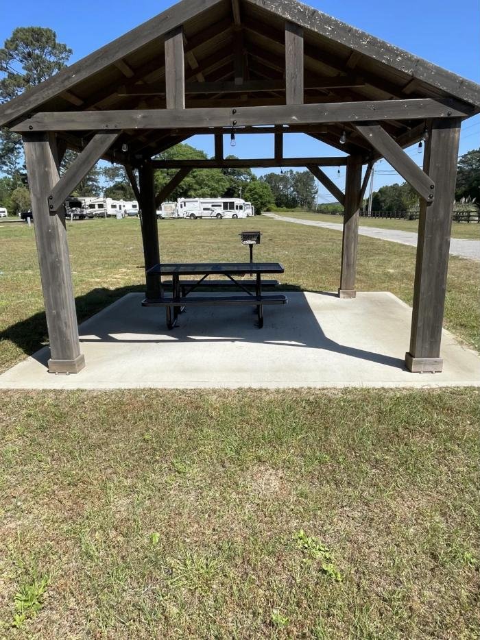 Picnic pavilion on open grass with RVs and trees in the background